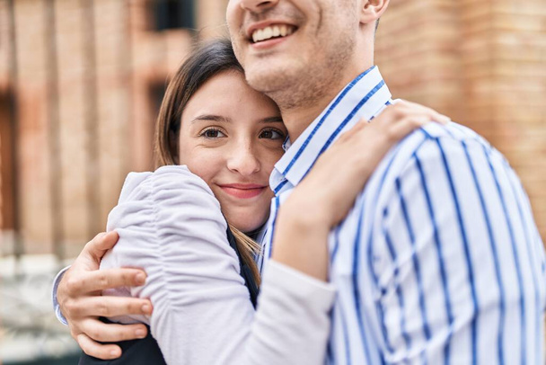 Чоловік і жінка пара посміхаються впевнено обіймаючи один одного на вулиці
 - Фото, зображення