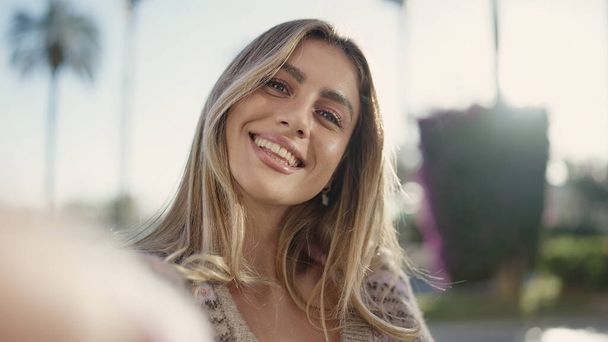 jong blond vrouw glimlachen zelfverzekerd maken selfie door camera op straat - Foto, afbeelding
