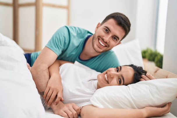 Jeune couple hispanique s'embrassant allongés sur le lit dans la chambre - Photo, image