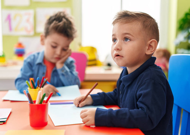 Schattige jongens kleuters zitten op tafel tekenend op papier op de kleuterschool - Foto, afbeelding