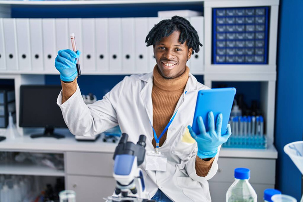 Afrikkalainen amerikkalainen mies tiedemies käyttäen kosketuslevy tilalla koeputki laboratoriossa - Valokuva, kuva