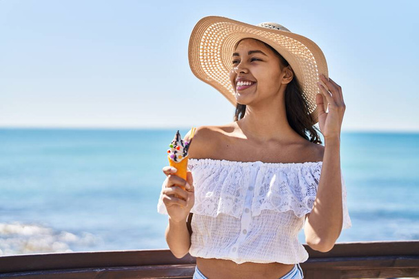 Young african american woman tourist smiling confident eating ice cream at seaside - Foto, immagini