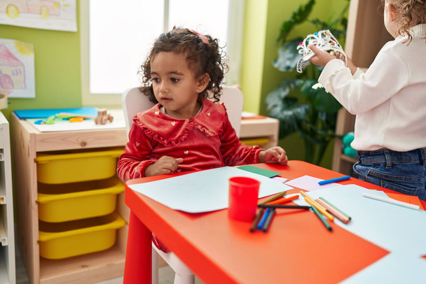 Entzückende Vorschulmädchen sitzen im Kindergarten am Tisch und zeichnen auf Papier - Foto, Bild