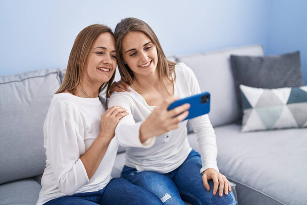 Two women mother and daughter make selfie by smartphone at home - Zdjęcie, obraz
