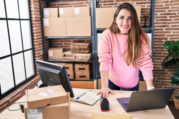 Young beautiful hispanic woman ecommerce business worker smiling confident standing at office - 写真・画像