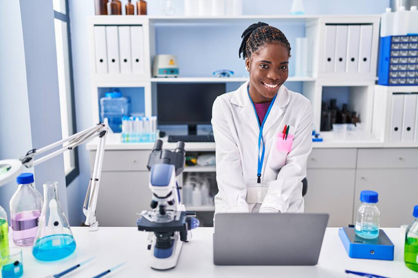Африканська американка в науковій формі за допомогою ноутбука в лабораторії. - Фото, зображення