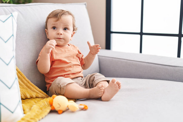 Adorable blond toddler sitting on sofa at home - Photo, Image