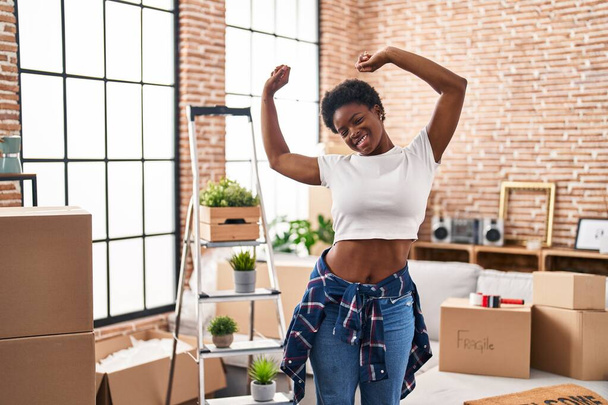 African american woman smiling confident stretching arms at new home - 写真・画像