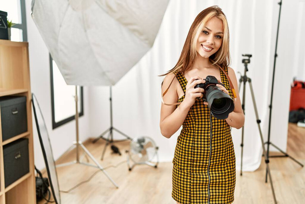 Young caucasian woman photographer holding professional camera photo studio - Fotó, kép