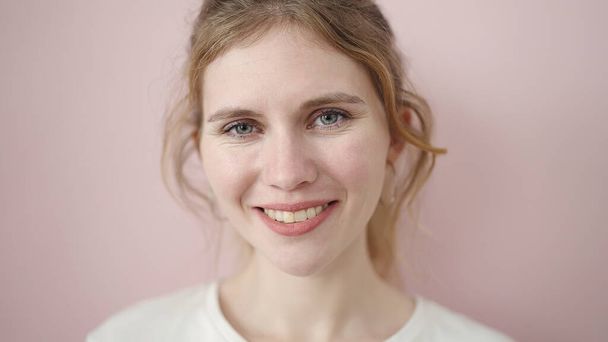 Young blonde woman smiling confident standing over isolated pink background - 写真・画像