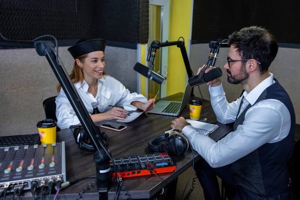 At the radio studio. Young girl talking with dark-haired man - Fotó, kép