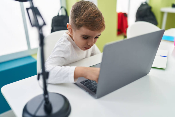 Suloinen latino poika opiskelija käyttää kannettavaa tietokonetta istuu pöydällä luokkahuoneessa - Valokuva, kuva