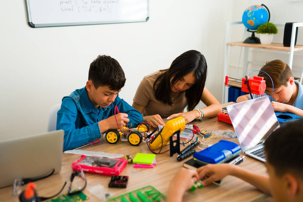 Gruppo latino di adolescenti che costruiscono robot mentre costruiscono circuiti elettronici e codificano l'apprendimento durante un progetto - Foto, immagini