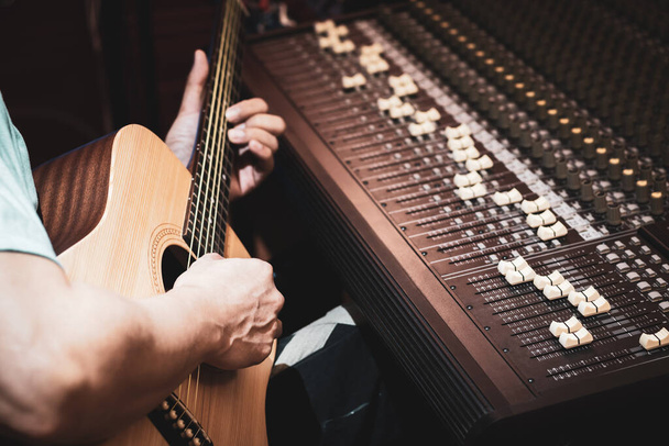 close-up mannelijke muzikant, componist die akoestische gitaar speelt in de studio. Opname of songwriting van akoestische muziekinstrumenten - Foto, afbeelding