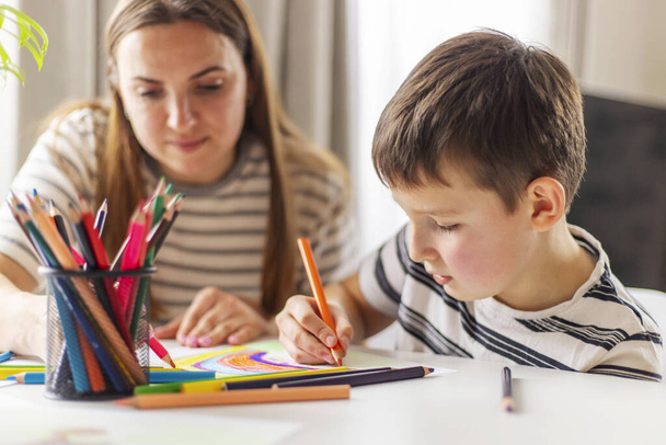 Mother and child drawing with pencils sitting at the desk at home. Happy family - 写真・画像