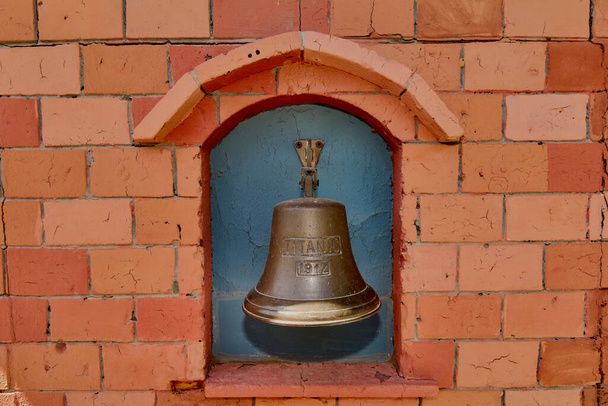 レンガの壁にブロンズ製の鐘が刻まれているタイタニック1912. - 写真・画像
