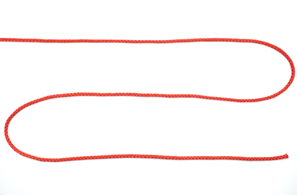 Corda rossa ritorta a forma di zig-zag su uno sfondo bianco isolato. Corda di nylon rosso si trova su uno sfondo bianco, vista dall'alto. Spazio libero per il testo - Foto, immagini