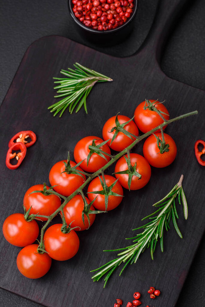 Delicious fresh cherry tomatoes on a twig on a dark concrete background. Vegetarian cooking - Photo, Image