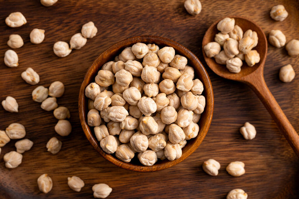 Chick pea uncooked beens. Studio shoot on wooden background. Beans spread on rustic scene.Up view shoot. - Photo, image