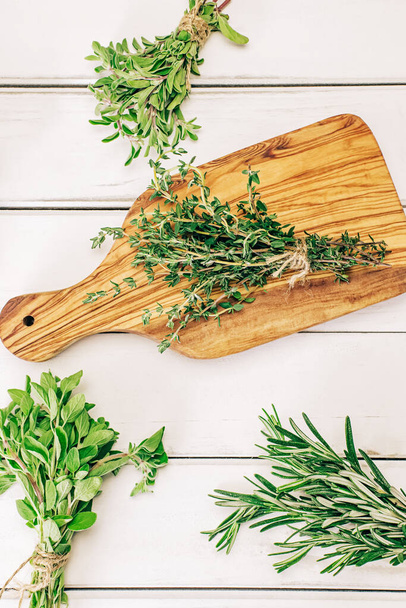 Various aromatic green herbs in bunches on the white table, top view - 写真・画像