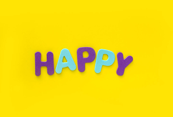 Glückliche Buchstaben auf gelbem Hintergrund mit Leerzeichen. Festkonzept. - Foto, Bild