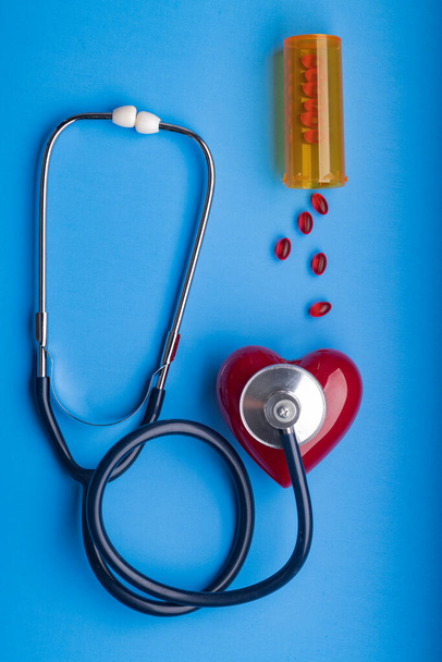 Medical Stethoscope, pills and red heart on blue background, top view. Space for text. - Photo, Image