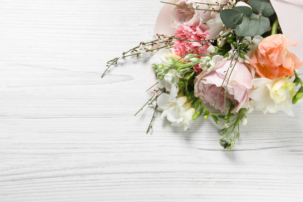 Μπουκέτο με όμορφα λουλούδια σε λευκό ξύλινο τραπέζι, από πάνω. Χώρος για κείμενο - Φωτογραφία, εικόνα