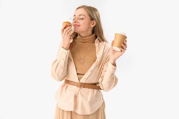 Fiatal nő csésze kávé eszik cupcake könnyű háttér - Fotó, kép
