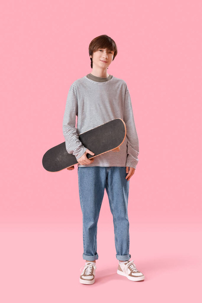 Teenage boy with skateboard on pink background - 写真・画像