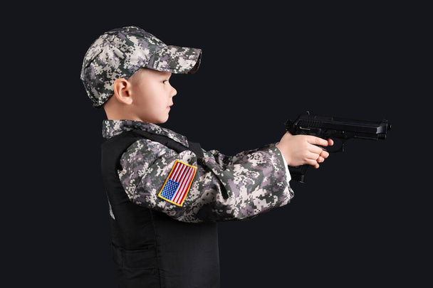 Cute little soldier with gun on black background - Foto, imagen
