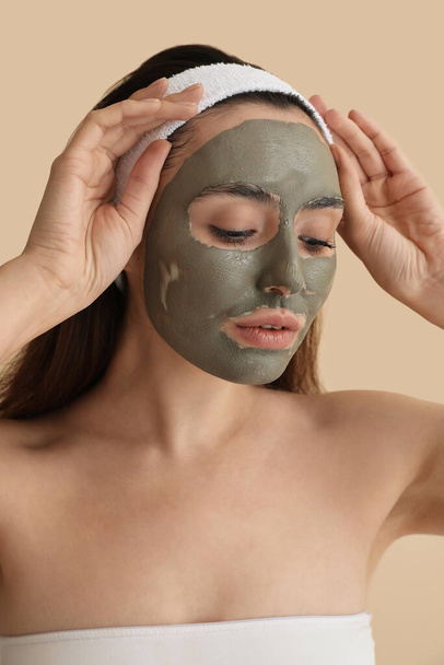 Young woman with applied clay mask on beige background, closeup - Photo, Image