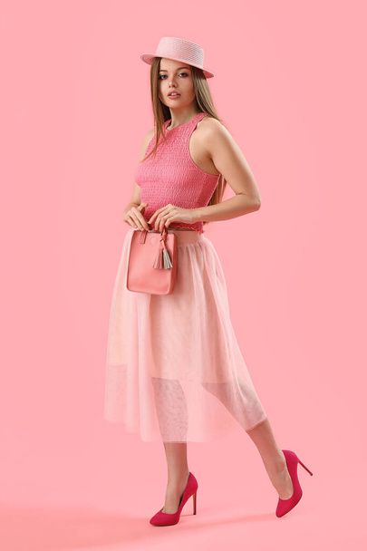Fashionable young woman in top and skirt on pink background - Fotó, kép