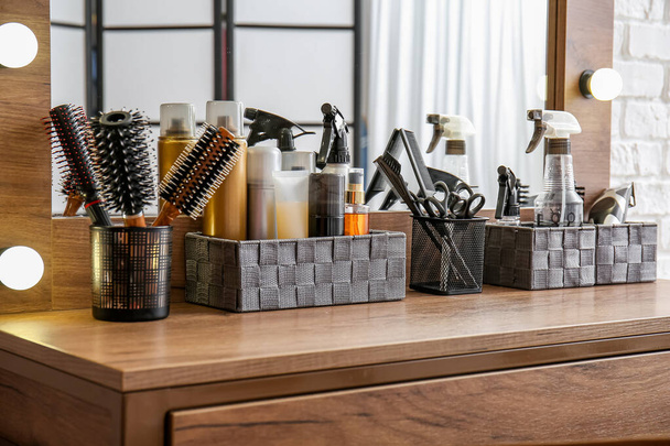 Organizzatori con diversi spray per capelli e accessori in tavola nel salone di bellezza - Foto, immagini