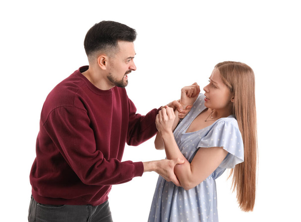 Angry young man hurting his wife on white background. Domestic violence concept - Φωτογραφία, εικόνα