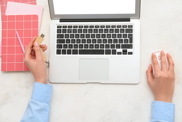 Frauenhände mit modernem Laptop, USB-Stick und Notebooks auf hellem Hintergrund - Foto, Bild