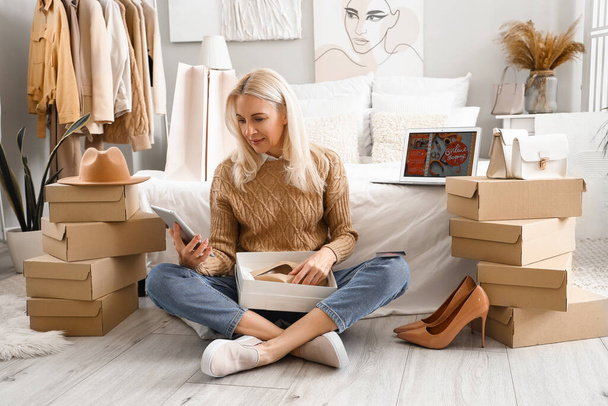 Femme mûre avec tablette et de nouvelles chaussures shopping en ligne dans la chambre - Photo, image
