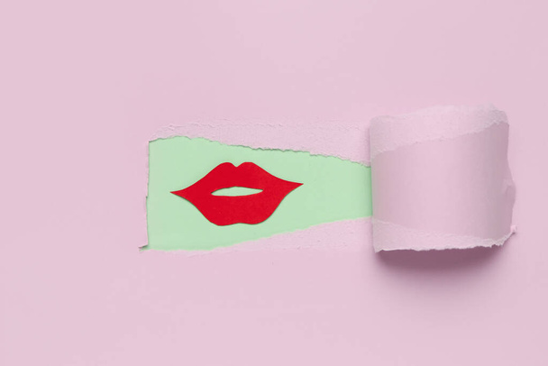 Red paper lips visible through hole in pink paper - Φωτογραφία, εικόνα