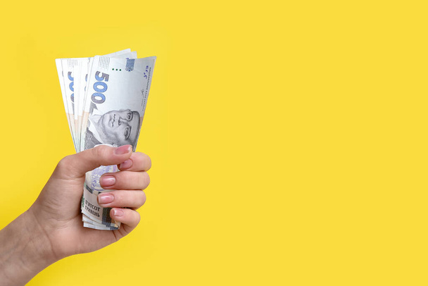 Woman with hryvnia banknotes on yellow background - Photo, Image
