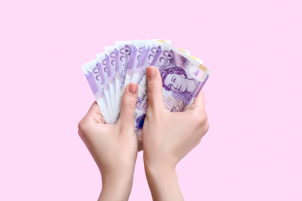 Woman with hryvnia banknotes on pink background - Фото, зображення