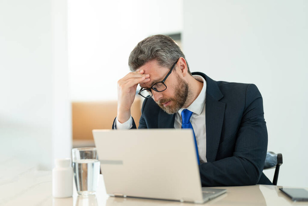 overworked man manager has pain and fatigue. photo of man manager has pain and fatigue. man manager has pain and fatigue in office. man manager has pain and fatigue while working. - Foto, Bild