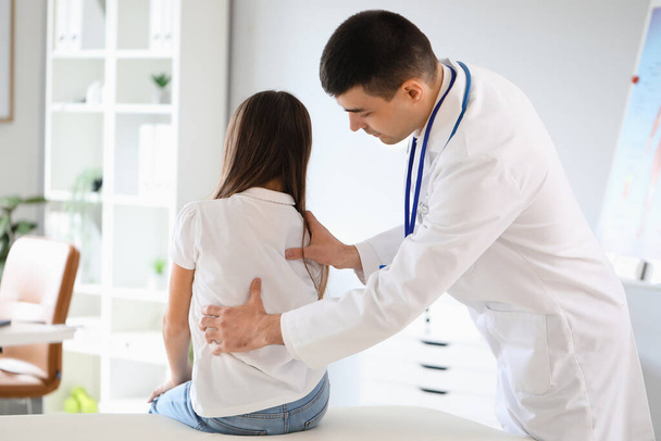 Doctor checking posture of little girl in clinic - Foto, Imagen