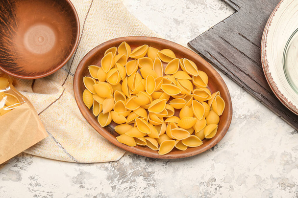 Bowl with raw conchiglie pasta on grunge background - Фото, изображение