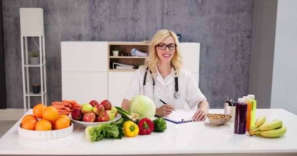 Portrait Of Female Dietician With Vegetables On Desk - Foto, immagini