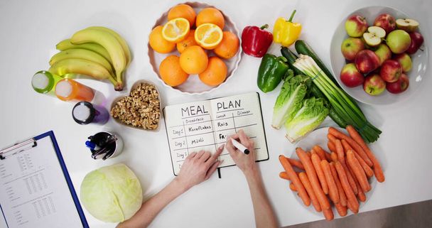 Женщина-диетолог пишет план питания в целях - Фото, изображение