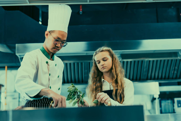 In culinary school, teenager learn from real chefs how to make sorts of tasteful food. Cooking spaghetti is a hands-on practice that engages students' sense of taste and smell as they follow recipes - Zdjęcie, obraz
