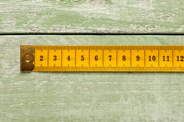 Yellow measuring tape on green wooden background - Photo, Image