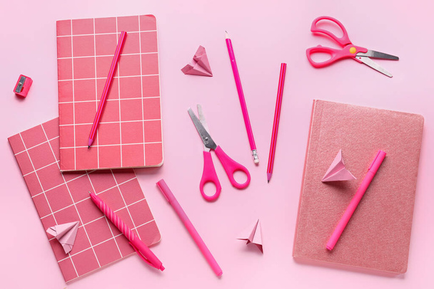Összetétel jegyzetfüzetekkel, írószer-készletekkel és rózsaszín hátterű papírsíkkal - Fotó, kép