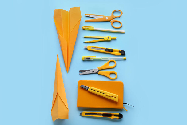 Composition with stationery supplies and paper planes on blue background - Фото, изображение