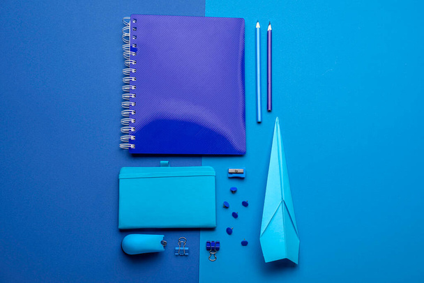 Kompozice s kancelářskými potřebami a papírovou rovinou na modrém pozadí - Fotografie, Obrázek