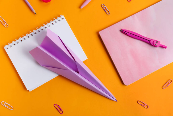 Composition with stationery supplies and paper plane on orange background - Photo, Image